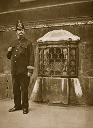 Policeman standing next to a stone set in the wall of St. Swithins, Cannon Street
